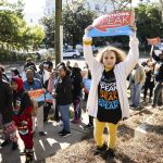 Young woman holding a survivors speak sign at a protest.