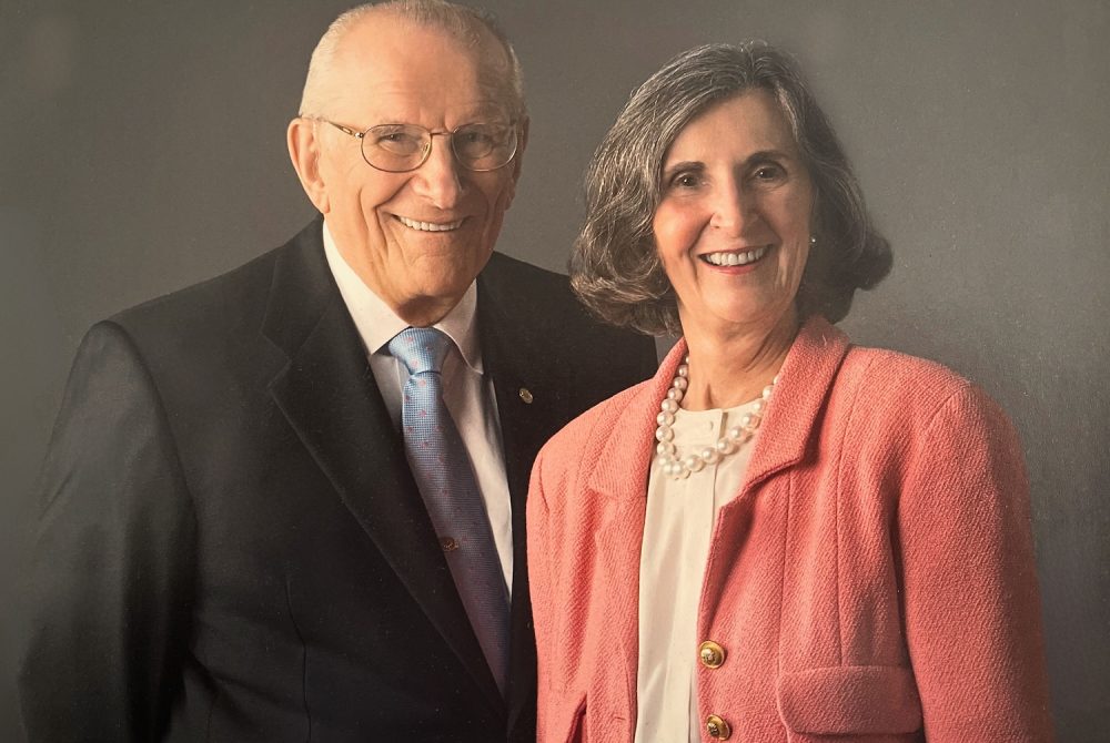 Article Banner - Stan Pauley, in a dark suit, stands beside Dorothy Pauley, in a salmon coat