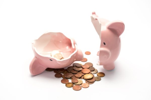 A broken piggy bank with small amount of coins spilled out.