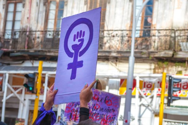 A woman holds up a sign depicting a raised fist inside the "woman" symbol, at a protest.