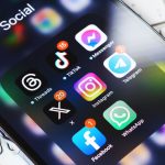 Article Banner - Social media icons on a phone screen with a white keyboard in the background.