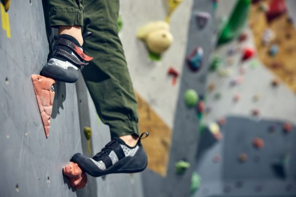 The feet of a rock climber scaling a wall.
