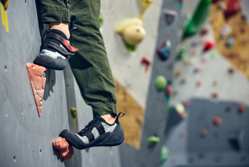 The feet of a rock climber scaling a wall.