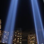 Article Banner - Twin blue lights mark the spot where the World Trade Center towers stood against a nighttime city background
