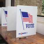 Voting booth dividers set up next to each other on a brown desk at a polling place.